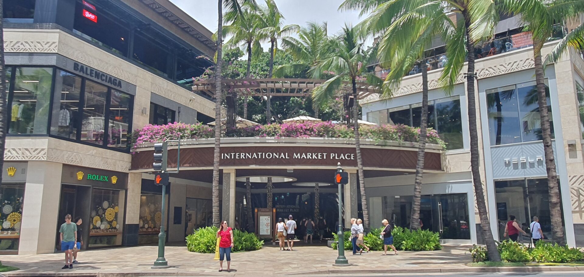 A group of people walking around in front of an international market place.